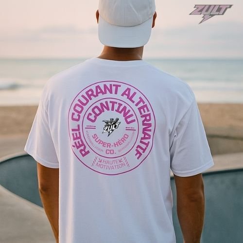 T-shirt blanc ZULT STAMP #2 Collection SIGNATURE avec motif rose “Courant Réel Alternatif Continu”, porté au bord de mer par un homme, design graphique inspiré électricité et super-héros.